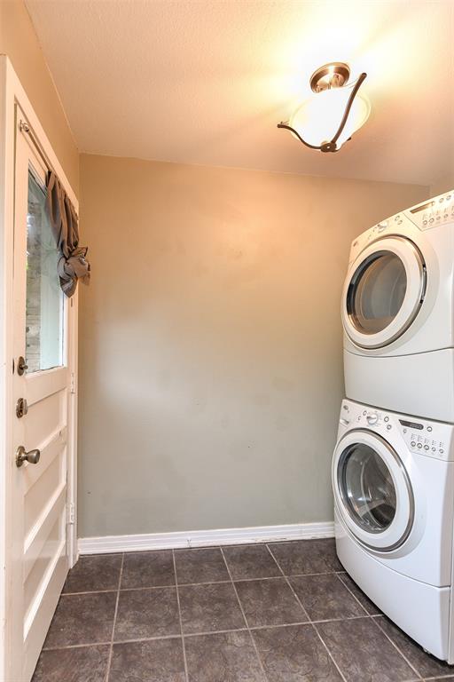 3516 Rashti Court Fort Worth, TX 76109 - Photo 12 of 24 Washroom featuring a textured ceiling, dark tile patterned flooring, and stacked washer and clothes dryer