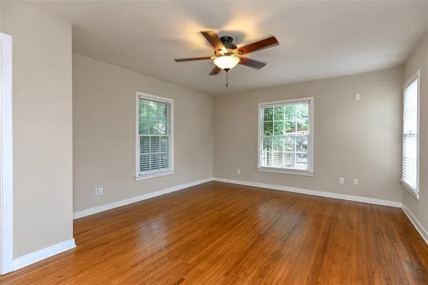 a view of an empty room with wooden floor and a window