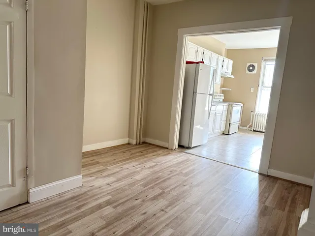 a view of a hallway with wooden floor and a bathroom