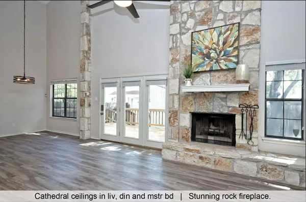 a view of a livingroom with wooden floor a fireplace and windows
