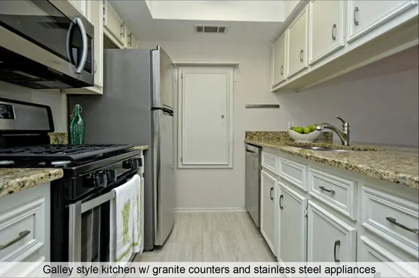 a kitchen with stainless steel appliances granite countertop a stove a refrigerator and a microwave