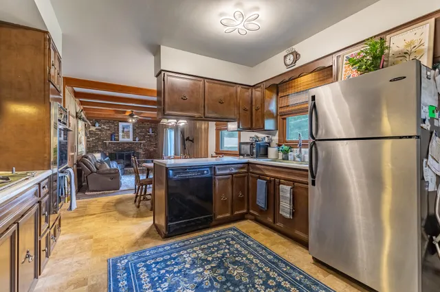 a kitchen with stainless steel appliances granite countertop a refrigerator a stove and a sink with wooden floor