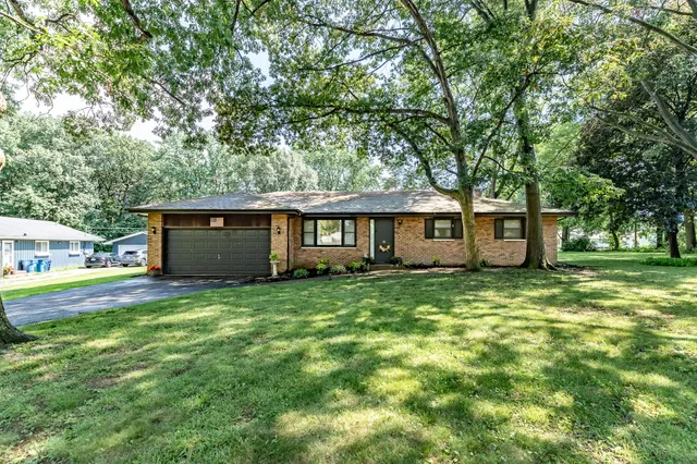 a view of a yard in front of a house with large tree