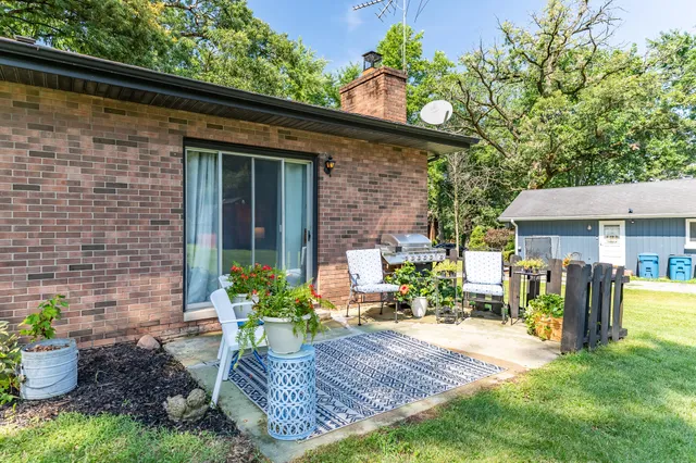 a view of a patio with table and chairs potted plants and floor to ceiling window