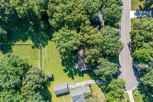 an aerial view of residential house with outdoor space and trees all around