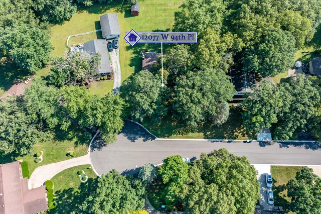 an aerial view of a house with a yard and trees all around