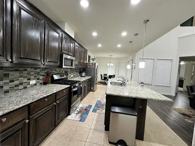 a kitchen with kitchen island granite countertop wooden cabinets and a refrigerator