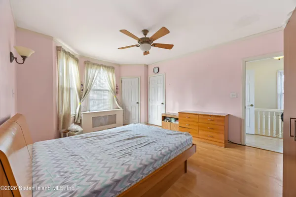 a bedroom with a bed dresser and a large window