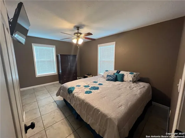 a bedroom with a bed ceiling fan and a window