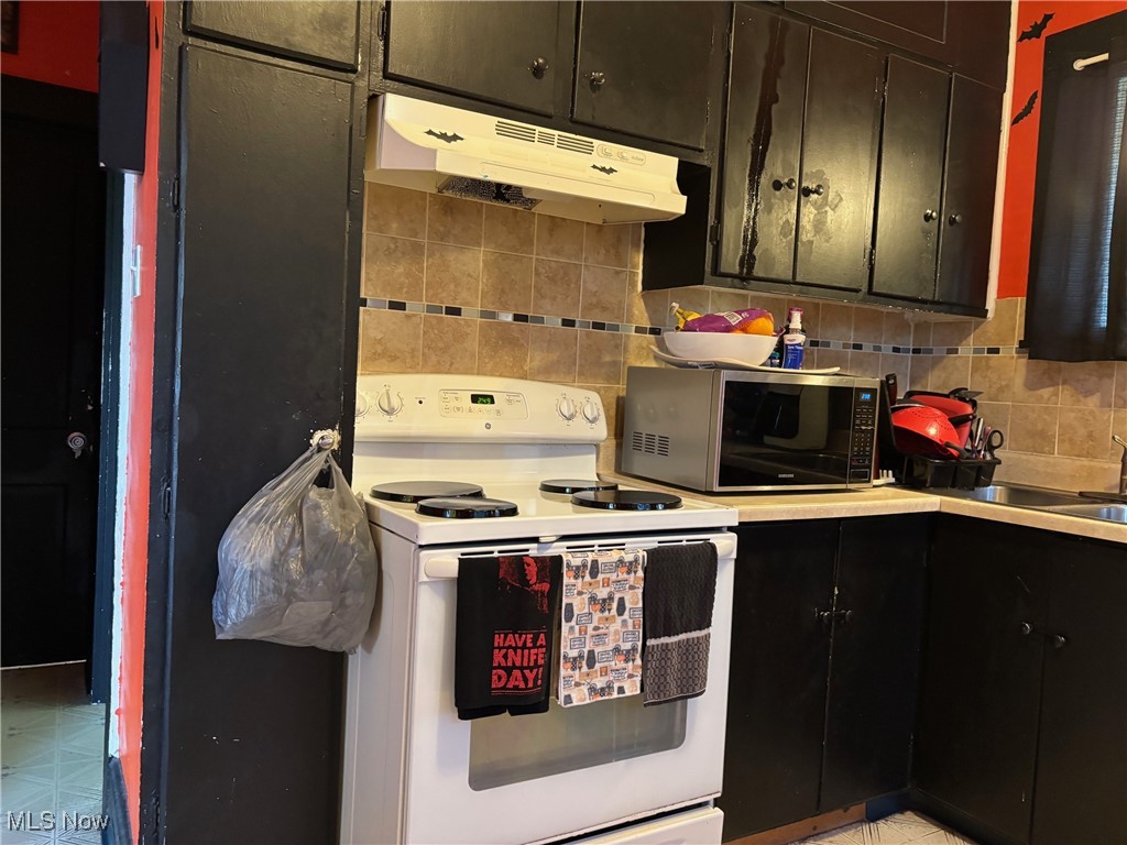 748 Bellview Road Cambridge, OH 43725 - Photo 8 of 20 Kitchen featuring white electric range oven, stainless steel microwave, under cabinet range hood, backsplash, and light countertops