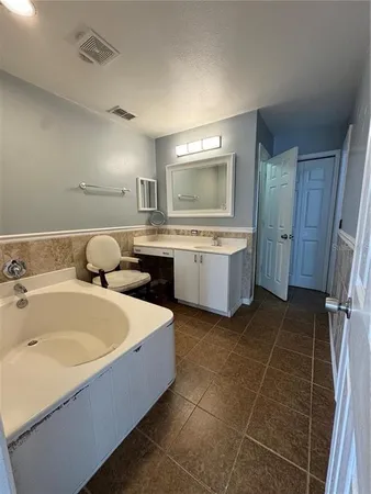 a spacious bathroom with a tub sink and mirror
