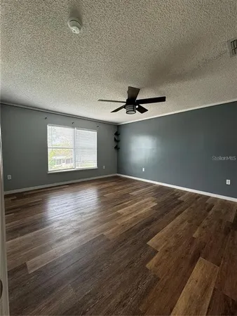 an empty room with wooden floor cabinet and windows