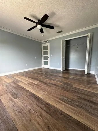 a view of an empty room with wooden floor and a ceiling fan