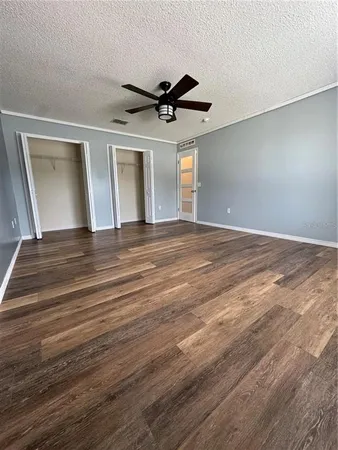 a view of an empty room with window and wooden floor