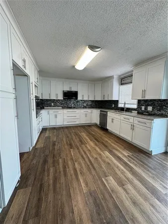 a large kitchen with wooden floors and stainless steel appliances