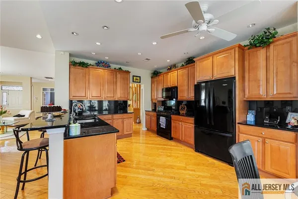 a kitchen with stainless steel appliances kitchen island granite countertop a refrigerator a stove a sink a dining table and chairs with wooden floor