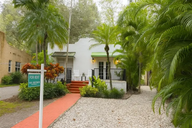 a view of a white house with a yard and potted plants