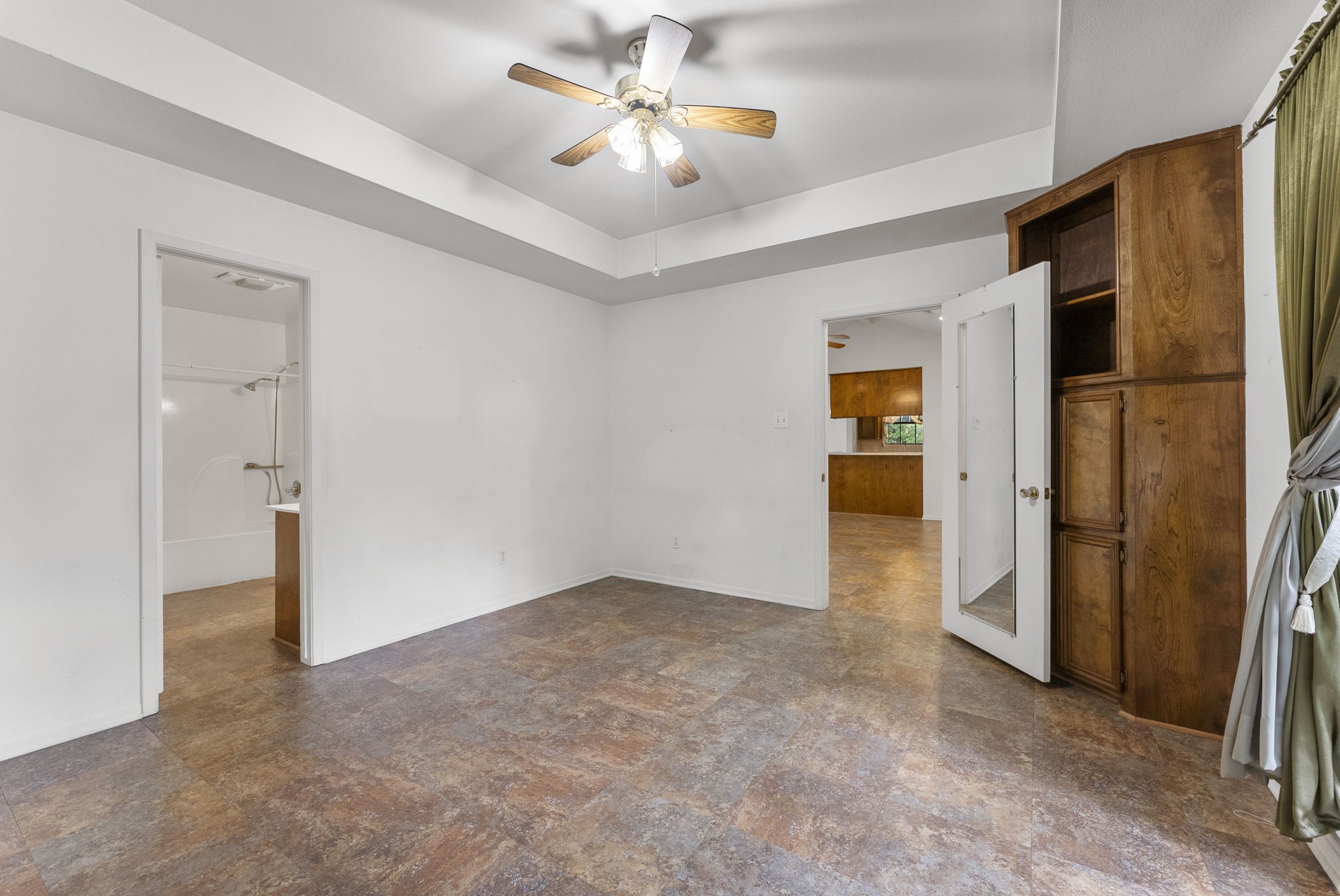 202 Sunset Boulevard Conroe, TX 77303 - Photo 31 of 50 Experience comfort and style in this inviting primary bedroom, featuring elegant tray ceilings, a ceiling fan, ample natural light, and convenient access to an en-suite bathroom and adjacent rooms.