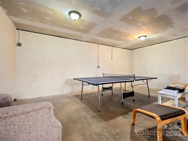 a view of a backyard with table and chairs potted plants and a brick wall