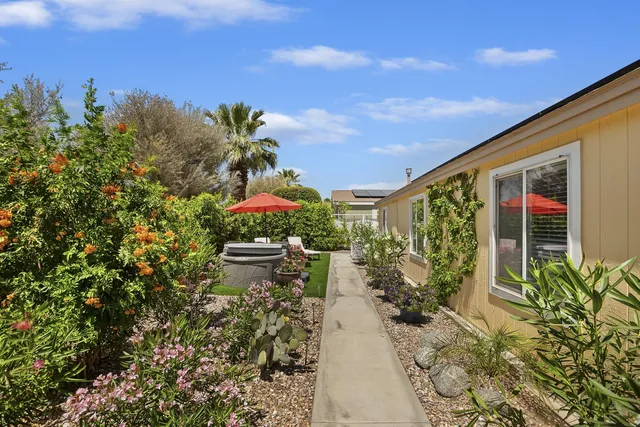 a view of a patio with couches table and chairs under an umbrella with a small yard