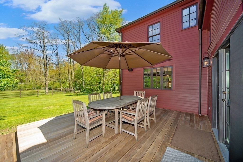 338 Neck Road Lancaster, MA 01523 - Photo 32 of 42 a view of a wooden deck with table and chairs under an umbrella