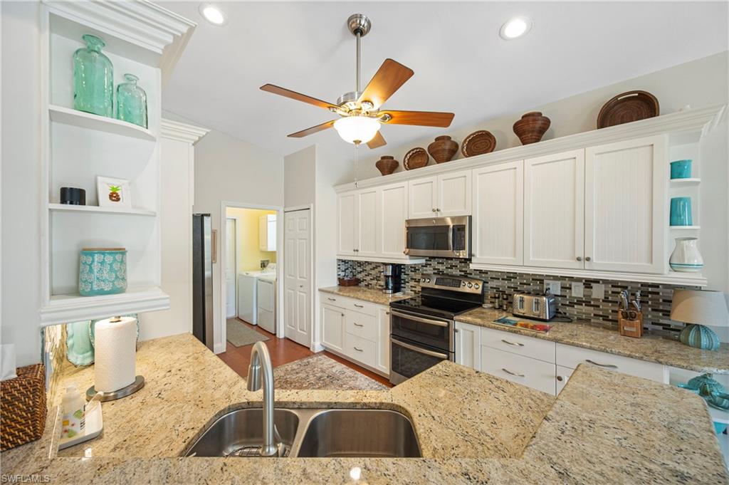 1742 Marsh Run Naples, FL 34109 - Photo 13 of 31 a kitchen with stainless steel appliances granite countertop a stove top oven a sink a dining table and chairs with wooden floor