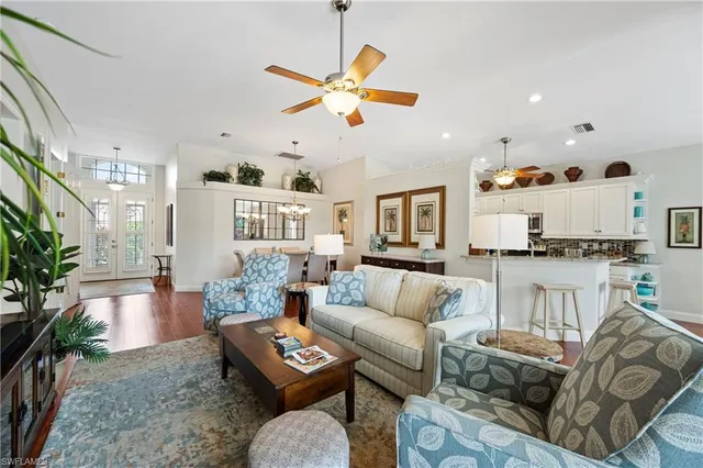a living room with furniture kitchen view and a chandelier