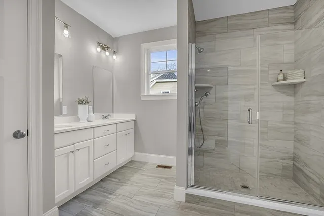 a bathroom with a double vanity sink a shower and a mirror