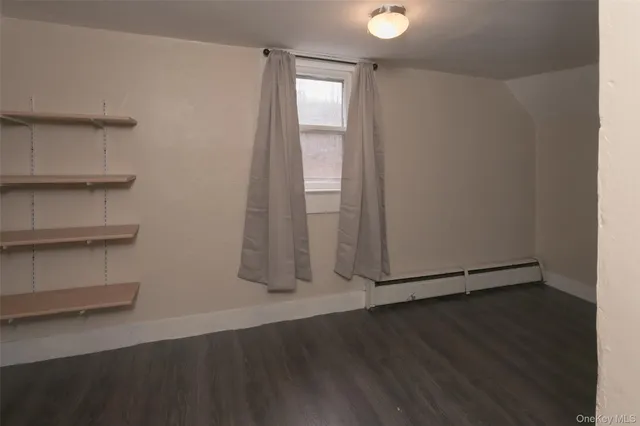 an empty room with wooden floor and cabinet
