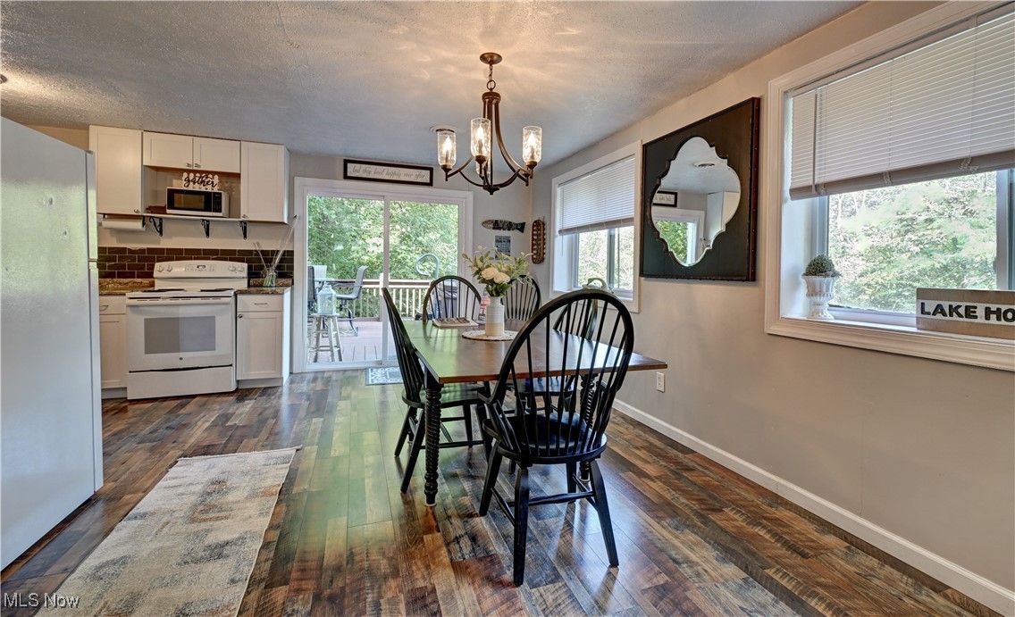 2227 Elk Road Southwest Carrollton, OH 44615 - Photo 23 of 40 Dining space featuring dark wood-style flooring, healthy amount of natural light, a chandelier, and a textured ceiling
