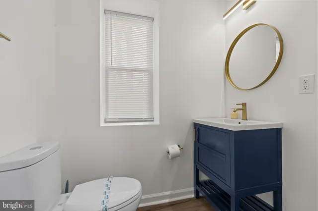 a bathroom with a toilet a sink a mirror and a window