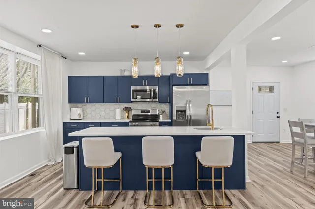 a kitchen with kitchen island granite countertop a dining table chairs refrigerator and sink