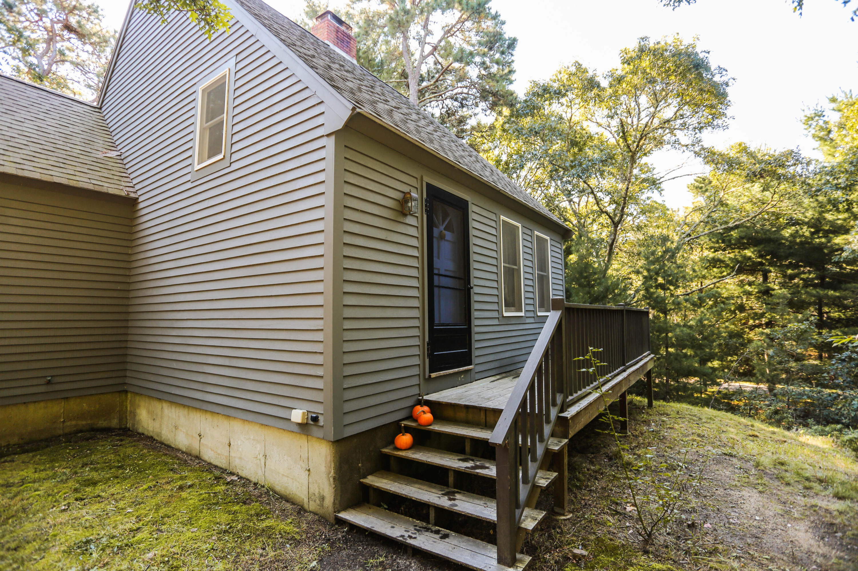 449 Poponessett Road Cotuit, MA 02635 - Photo 3 of 17 a backyard of a house with wooden fence and large trees