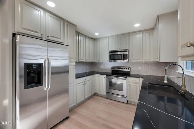 a kitchen with granite countertop a refrigerator and a stove top oven