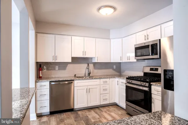 a kitchen with granite countertop a refrigerator stove and microwave
