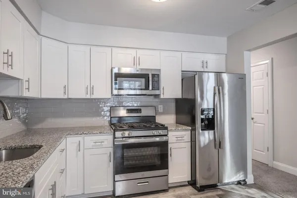 a kitchen with granite countertop a refrigerator sink and stainless steel appliances