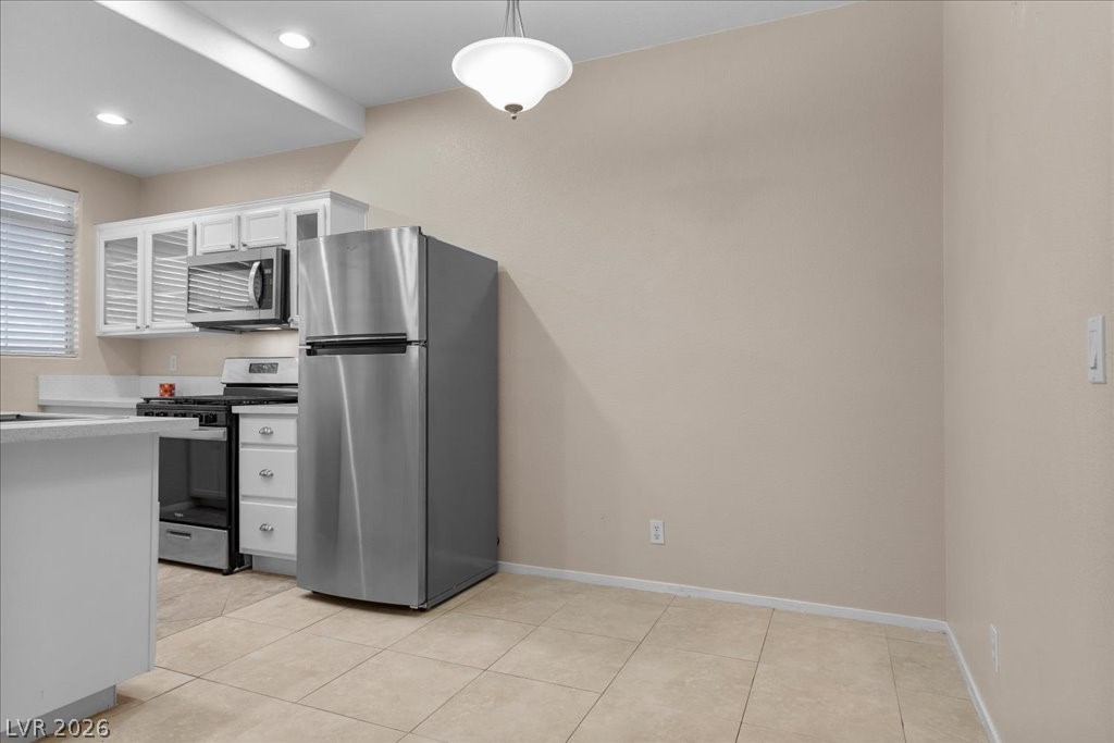 2201 Ramsgate Drive, Unit 818 Henderson, NV 89074 - Photo 8 of 32 Kitchen featuring stainless steel appliances, white cabinets, pendant lighting, glass fronted cabinets, and light tile patterned floors