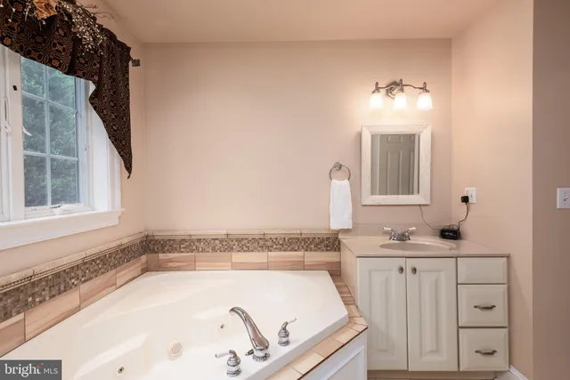 a bathroom with a tub sink and mirror