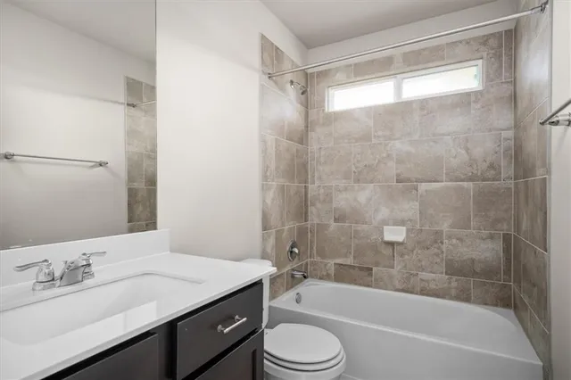 a bathroom with a granite countertop bathtub shower sink vanity mirror and toilet