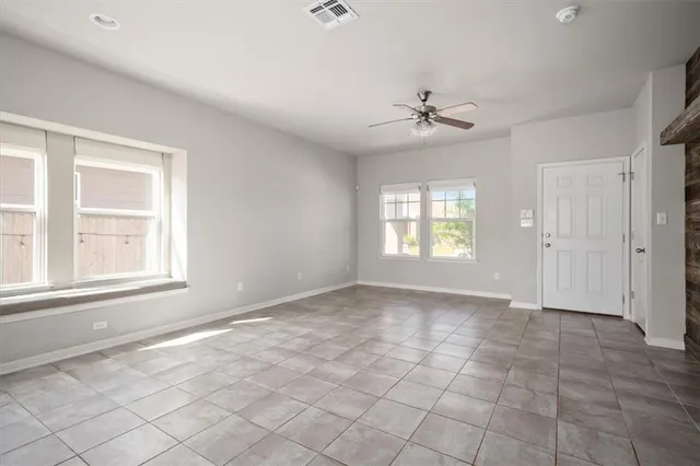 an empty room with windows and chandelier fan