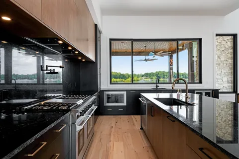 a kitchen with stainless steel appliances kitchen island granite countertop a refrigerator a sink a stove top oven and a refrigerator