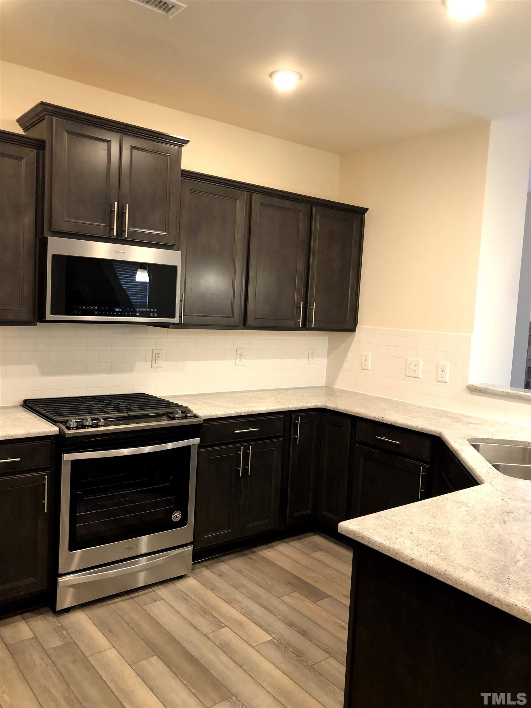1215 Merrion Avenue Durham, NC 27703 - Photo 6 of 19 a kitchen with stainless steel appliances a stove a microwave and sink