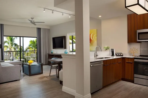 a open kitchen with stainless steel appliances granite countertop a sink dishwasher stove and refrigerator with wooden floor