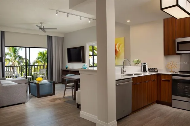 a open kitchen with stainless steel appliances granite countertop a sink dishwasher stove and refrigerator with wooden floor