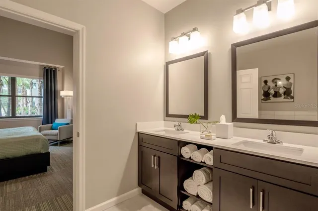 a en suite bathroom with a double vanity sink a large mirror and a bathtub