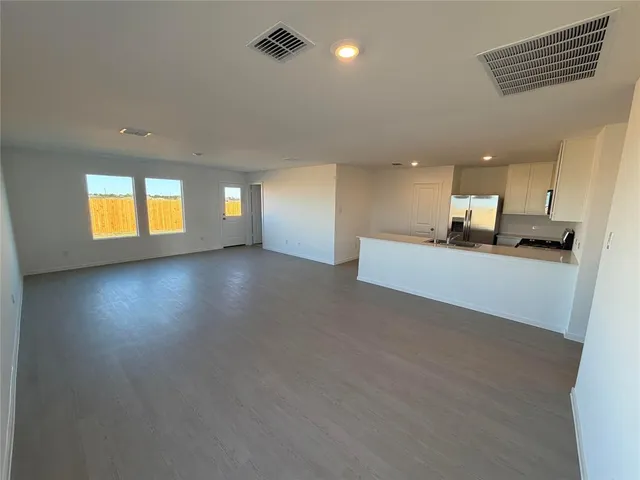 an empty room with a kitchen and windows