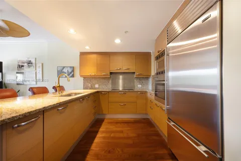 a kitchen with stainless steel appliances granite countertop a sink and a refrigerator