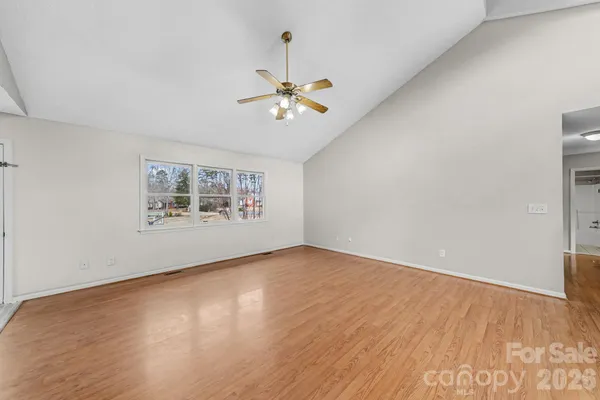 a view of an empty room with wooden floor and a chandelier