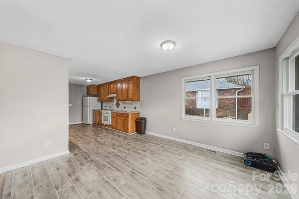 a view of an empty room with a window and wooden floor