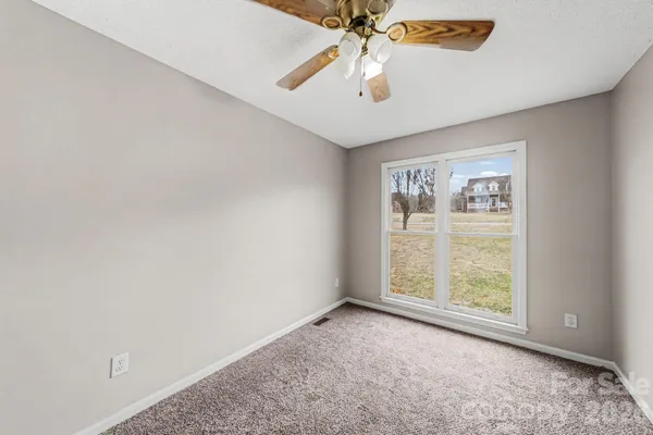 an empty room with a chandelier fan and a ceiling fan